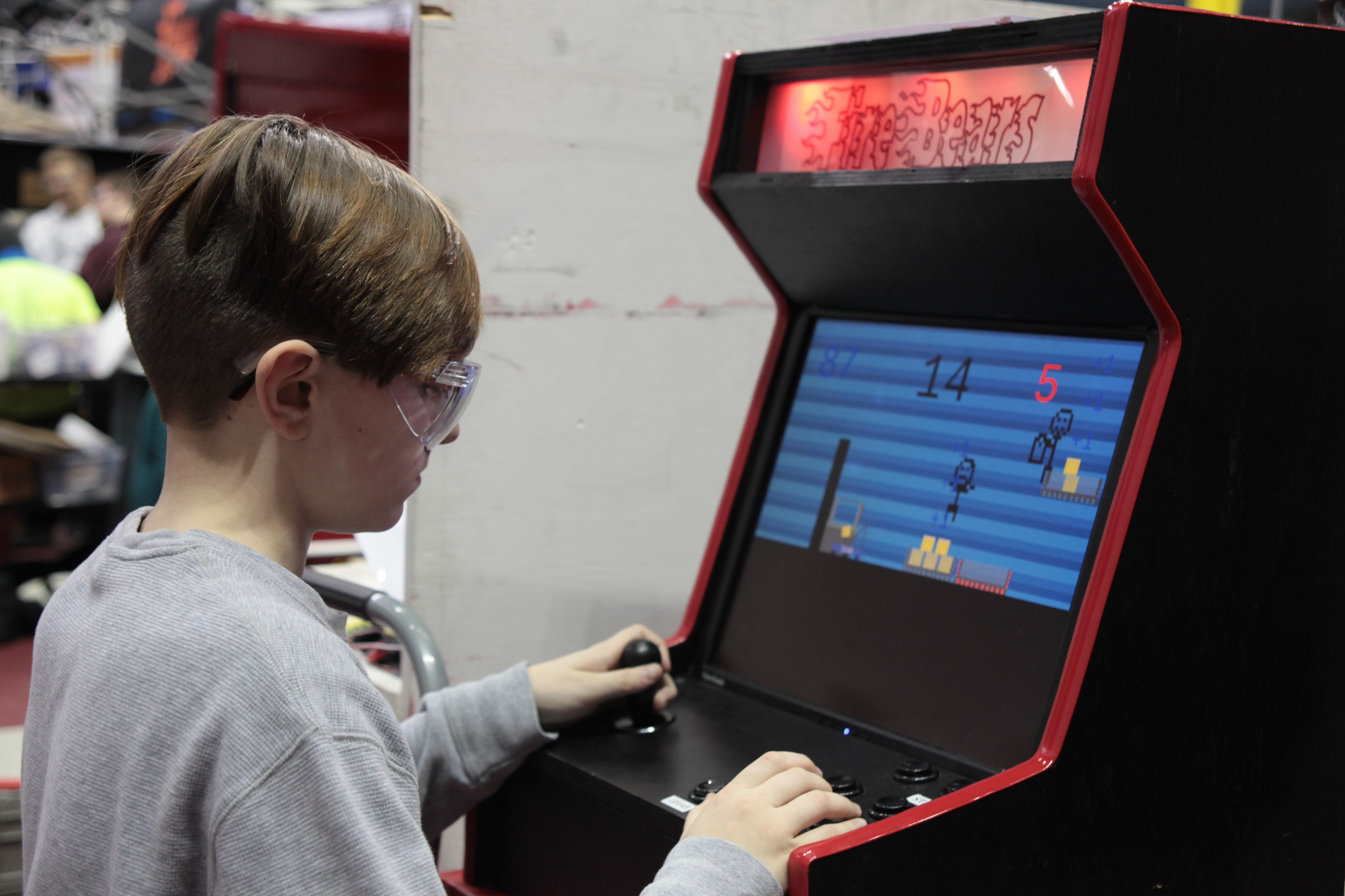 Image of boy playing game on arcade cabinet